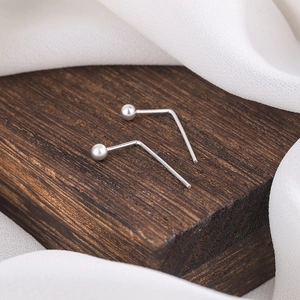 Minimalist S925 silver L-shaped nose studs with 2mm ball top on rustic wood block