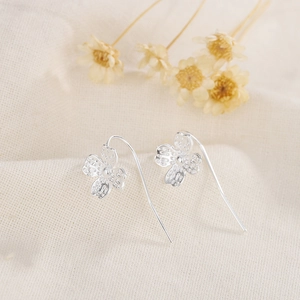 Elegant 925 sterling silver cherry blossom drop earrings on rustic linen background