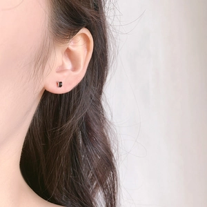 Minimalist black S925 sterling silver stud earrings on a model's ear in close-up shot