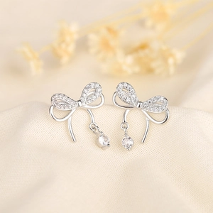 Elegant S925 silver double bow earrings with sparkling cubic zirconia on silk backdrop