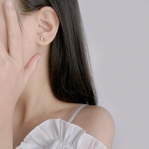 Élégantes boucles d'oreilles papillon s925 dorées portées par un mannequin au look épuré