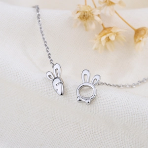 Boucles d'oreilles asymétriques lapin et carotte avec chaîne en argent sur tissu texturé
