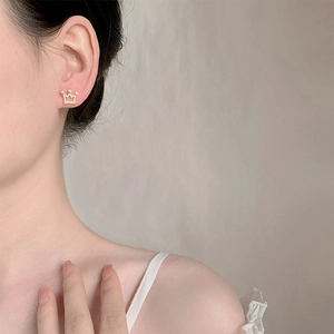 Élégante boucle d'oreille couronne en or avec diamants portée par un mannequin chic