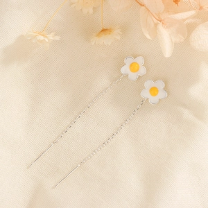 Elegant daisy flower dangle earrings with white petals and yellow centers on linen