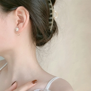 Close-up of a daisy floral earring worn by a model featuring white petals and yellow centers