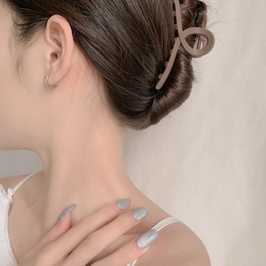 Silver hollow flower hoop earrings worn by a model in a minimalist style