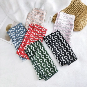 Collection of colorful chain print square silk scarves displayed on a white textured background