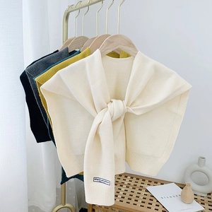Detail of multi-color knitted shawl scarves hanging on a rack in a minimalist room