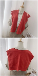 Detail of red knitted shawl vest with ribbed hem and woven label on linen shirt