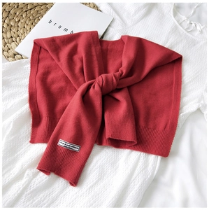 Detail of red knitted shawl featuring a minimalist fabric label on a lace background