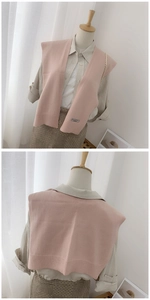 Detailed knit texture of pink shawl with ribbed hem and woven label decoration