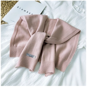 Detail of pink knitted shawl wrap with minimalist white label on soft textured fabric