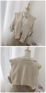 Detail of beige knitted shawl wrap featuring a decorative label on soft woven fabric