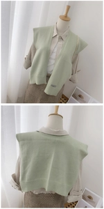 Close-up detail of light green knitted shawl with vertical ribbed texture and logo label