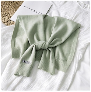 Detail of light green knitted shawl with ribbed cuffs and Korea label on white dress