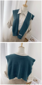 Detail of dark teal knitted shawl with ribbed edges and decorative fabric label