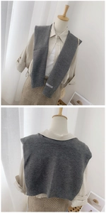 Detail of grey knitted shawl with white woven label showing texture and styling on a shirt