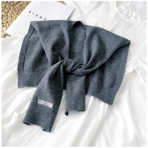 Close-up of dark grey knitted shawl scarf with fine ribbed texture and white woven label
