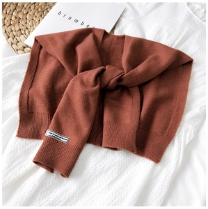 Close-up of brick red knitted shawl with twisted knot detail and Korean woven label
