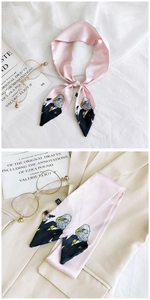 Detailed view of pink silk twilly scarf with cartoon eagle illustration on satin fabric