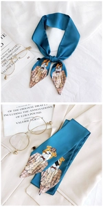 Detailed close-up of peacock blue silk twilly scarf with cartoon bulldog pattern