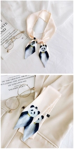Detail view of pink satin scarf featuring cute panda illustration and luxury book prop