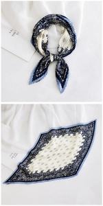 Detail of pleated silk scarf featuring navy and cream paisley patterns in diamond shape