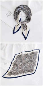 Detailed view of ivory pleated silk scarf with paisley patterns and navy blue edges