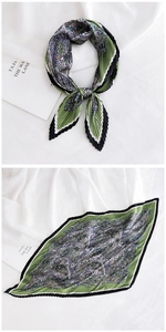 Close-up of pleated silk scarf featuring green paisley patterns and striped edges