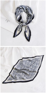 Detailed view of a navy blue pleated diamond-shaped silk scarf with floral paisley patterns