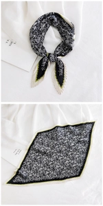 Macro detail of pleated paisley silk scarf featuring black, white and green pattern accents