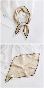 Close-up of pleated champagne silk scarf with navy zigzag edges and accordion folds
