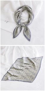 Detail of pleated grey paisley square scarf with delicate texture and stylish fold pattern