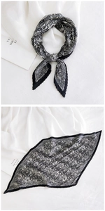 Detail of black and white paisley pleated scarf with refined plissé texture and elegant knot