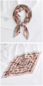 Detailed view of pink pleated square scarf with floral print and gray striped edges