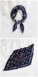 Detailed view of dark blue pleated square scarf with floral print and silk texture