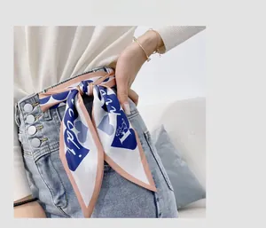 Detail of silk scarf tied as a stylish belt accessory on denim jeans for women