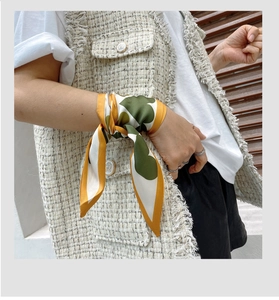 Detail showing silk-texture twilly scarf with heart print worn as a chic wrist accessory