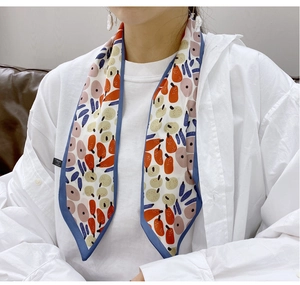 Detail of floral pattern silk scarf tied around neck showing abstract fruit prints