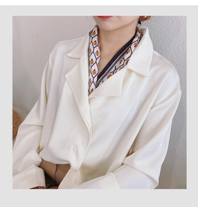 Close-up of cream satin shirt with elegant ladybug print silk scarf tied at collar