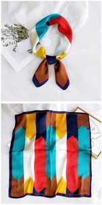 Detail view of square silk-like scarf featuring multi-color geometric block patterns