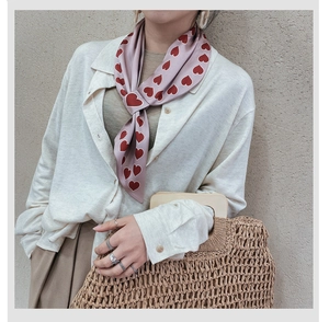 Detail of silk-like neck scarf with red heart pattern knotted on a model's neck