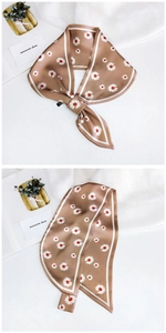 Detail of champagne brown silk scarf featuring white daisy prints and satin finish texture