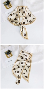 Detail of cream daisy print silk scarf tied in a bow with smooth satin texture