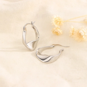 Polished S925 sterling silver hoop earrings with a twisted design on textured beige cloth
