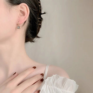 Elegant gold hook earrings featuring square grey cubic zirconia on a model