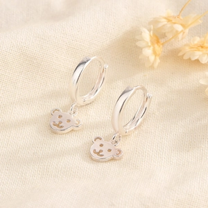 Orecchini a cerchio minimalisti in argento con orsetto su sfondo in lino testurizzato