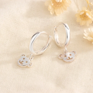 Orecchini a cerchio minimalisti in argento con ciondoli a orsetto su sfondo in tessuto