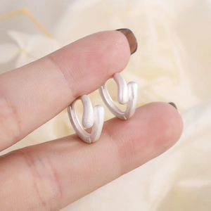Orecchini a cerchio in argento opaco con design a onde su sfondo floreale