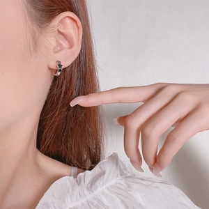 Chic silver hoop earrings with black five-pointed stars on model ear, 2023 trend